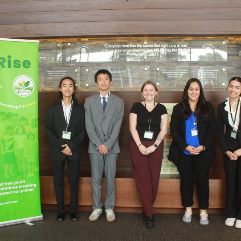 Group of five posing by the EcoRise Green Dream banner