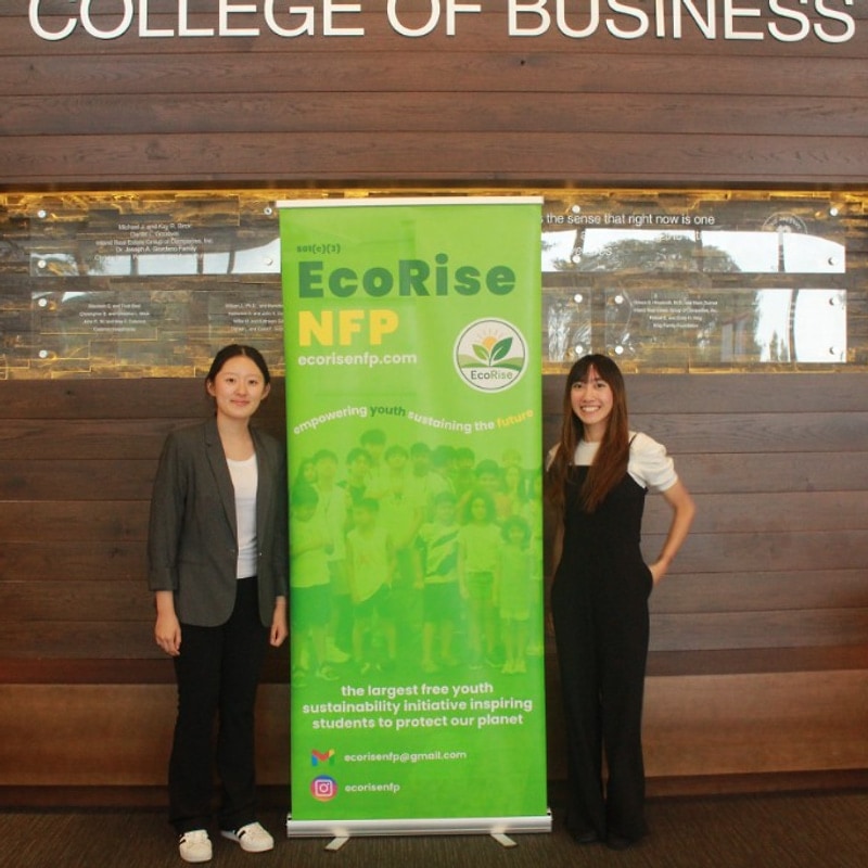 Two women posing by the EcoRise Green Dream banner