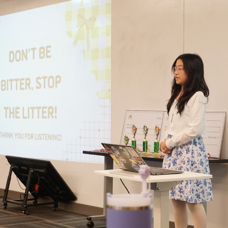 Student presenting a Don’t Be Bitter, Stop the Litter advocacy slide