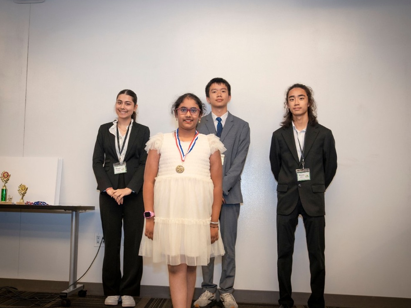 Shaanvi Mokshagundam with a medal for Reducing Litter seventh place, with mentors standing behind