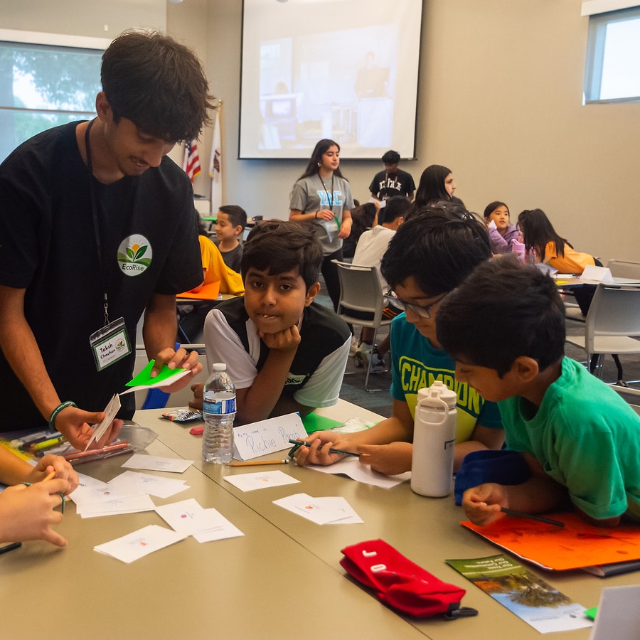 EcoRise mentor guiding students through a hands-on workshop activity