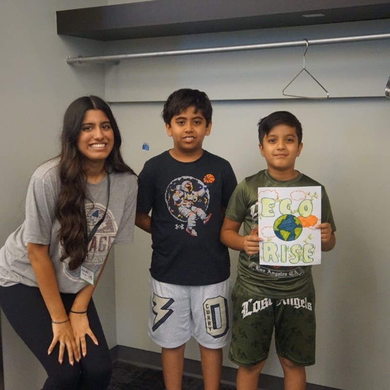 EcoRise mentor and students smiling with a handmade EcoRise poster