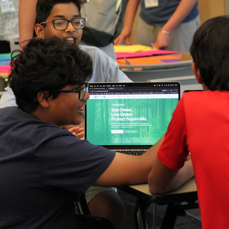 EcoRise campers gathered around a laptop with a See Green. Live Green. Protect Naperville poster