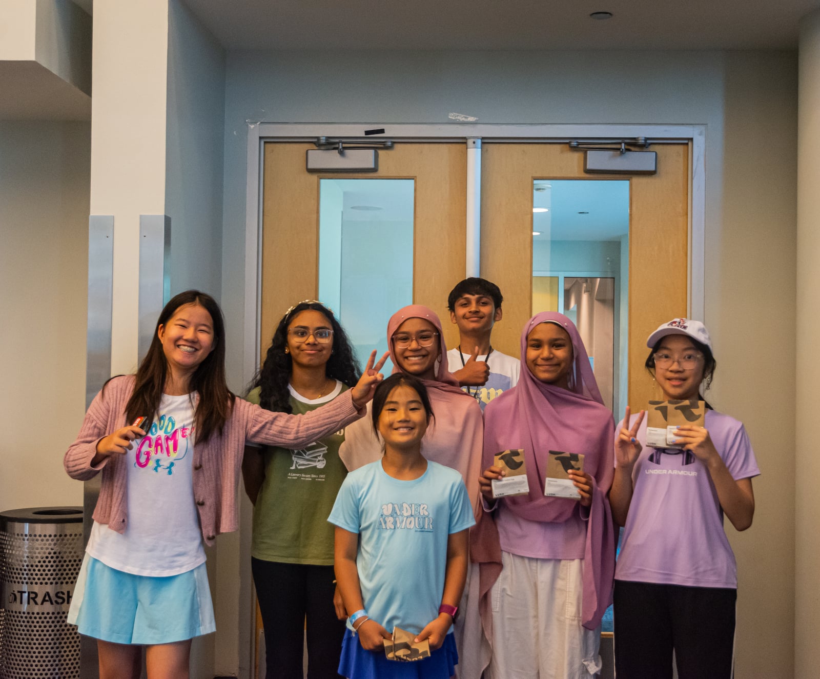 EcoRise camp students smiling together in front of wooden doors after a workshop
