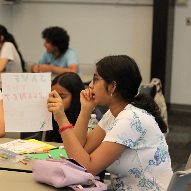 Student holding a Save the Planet poster at camp