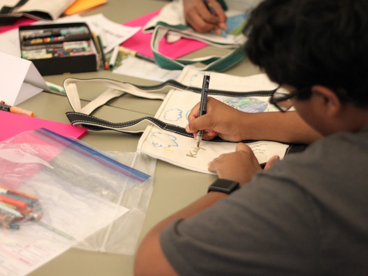 Student decorating a tote bag with Posca markers